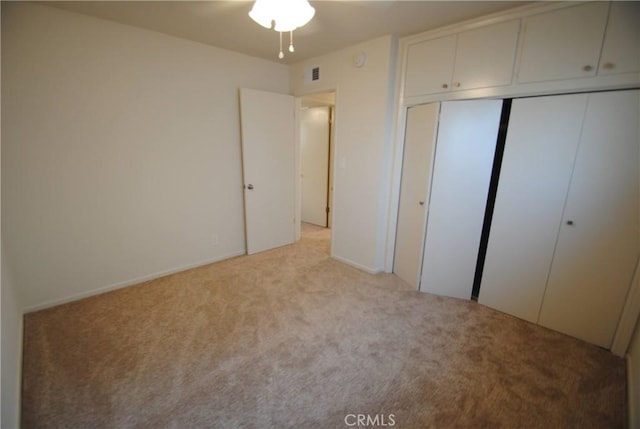 unfurnished bedroom featuring visible vents, light colored carpet, and a closet