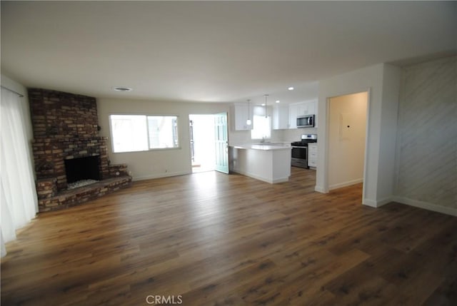 unfurnished living room with recessed lighting, baseboards, a fireplace, and dark wood-style flooring