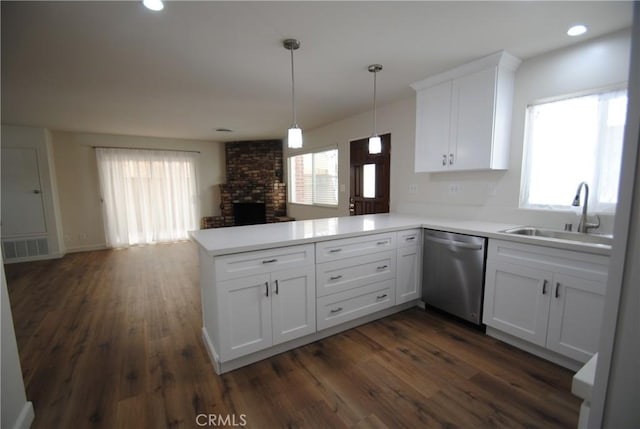 kitchen with open floor plan, a peninsula, stainless steel dishwasher, white cabinetry, and a sink