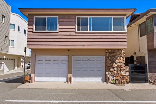 view of front of home featuring stone siding, stucco siding, and an attached garage