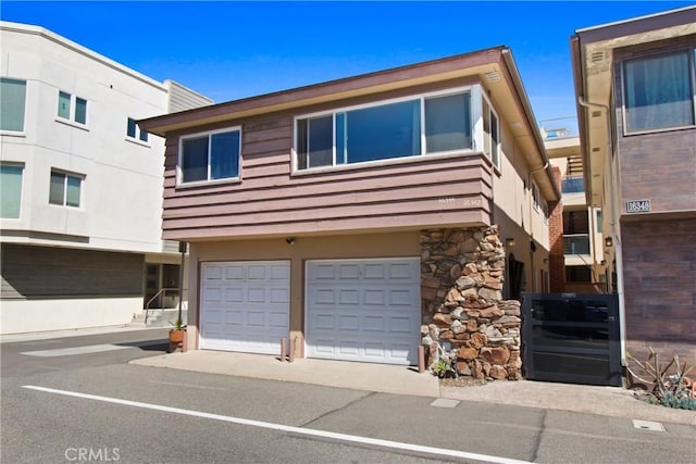 multi unit property featuring stone siding and an attached garage