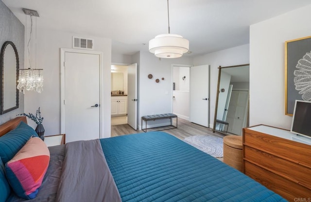 bedroom featuring visible vents, ensuite bath, and wood finished floors