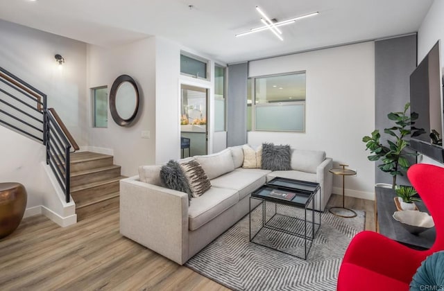 living room featuring stairway, baseboards, and wood finished floors