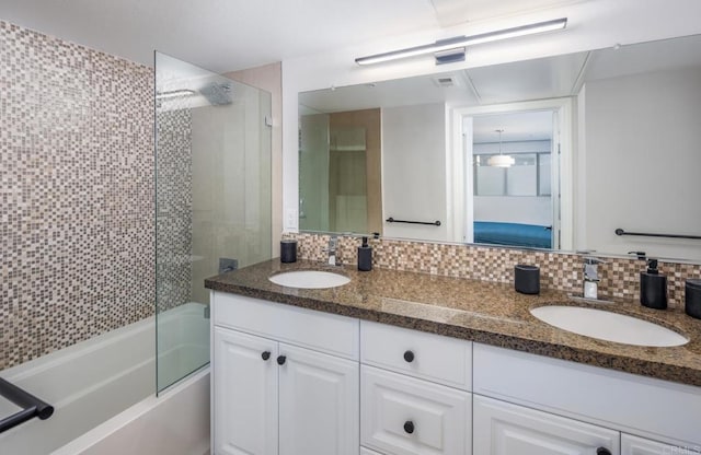 bathroom featuring double vanity, backsplash,  shower combination, and a sink