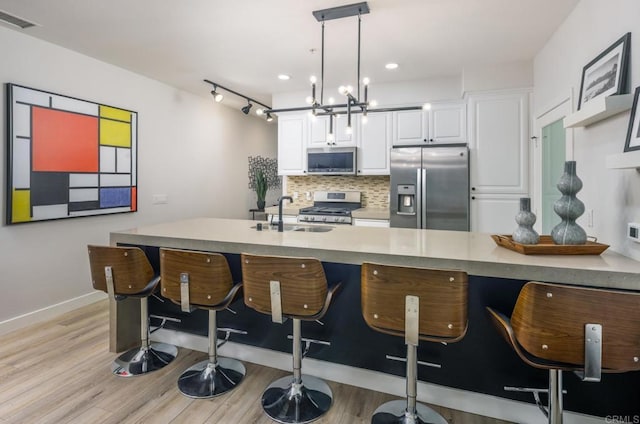 kitchen with visible vents, a sink, white cabinetry, stainless steel appliances, and decorative backsplash