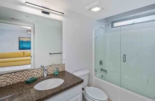 bathroom featuring visible vents, toilet, backsplash, shower / bath combination with glass door, and vanity