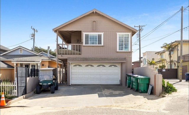 view of front of property with a balcony, concrete driveway, a garage, and fence