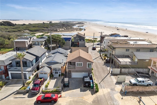 drone / aerial view featuring a water view, a beach view, and a residential view