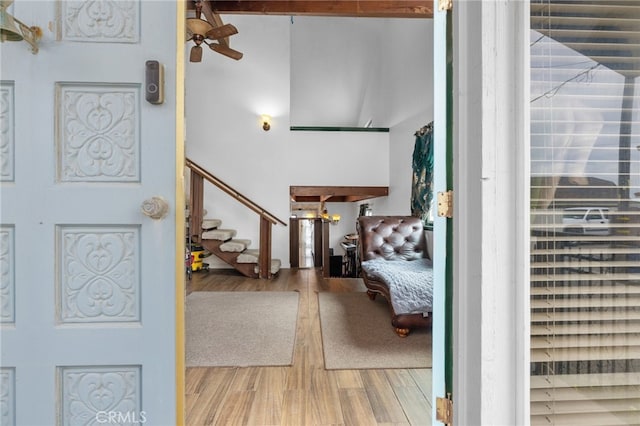 entrance foyer with a ceiling fan, stairs, a high ceiling, and wood finished floors