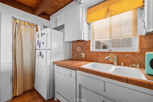 kitchen with decorative backsplash, light tile patterned flooring, white appliances, white cabinetry, and a sink