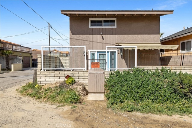 view of front of property featuring stucco siding and fence