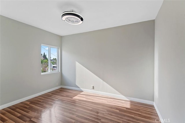 spare room featuring baseboards and wood finished floors