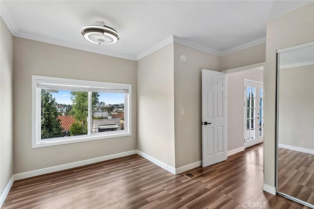 unfurnished room with wood finished floors, baseboards, and ornamental molding