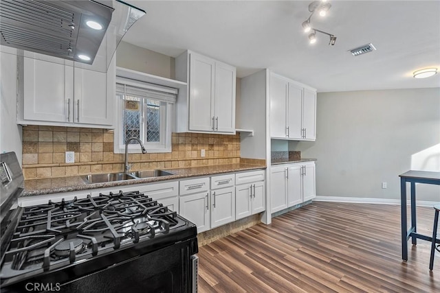 kitchen featuring visible vents, range with gas stovetop, exhaust hood, white cabinetry, and a sink