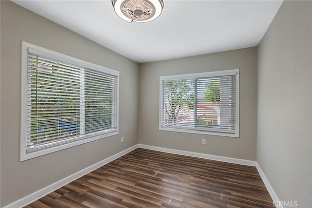 spare room featuring visible vents, baseboards, and dark wood-style flooring