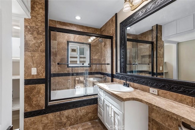 bathroom featuring tiled shower / bath combo, tile walls, and vanity