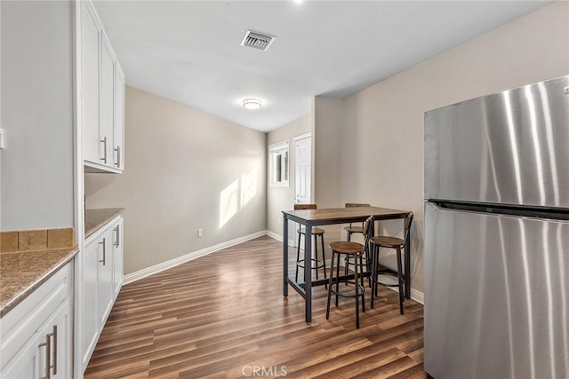 dining space featuring visible vents, baseboards, and dark wood-type flooring