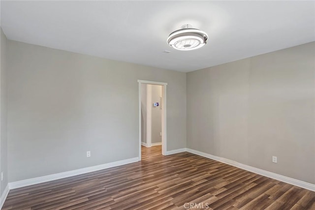 spare room featuring baseboards and dark wood-style floors