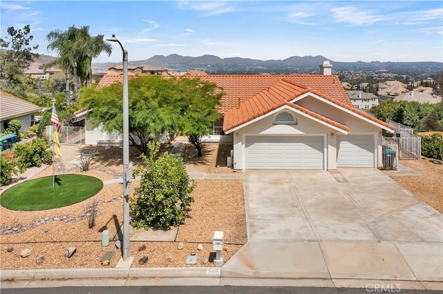 view of front of home with fence, a tiled roof, stucco siding, driveway, and a mountain view