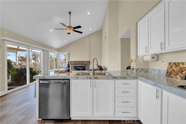 kitchen featuring a sink, a peninsula, white cabinetry, and stainless steel dishwasher