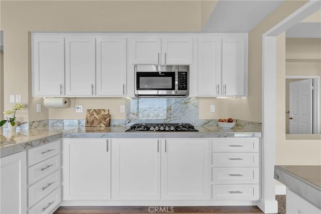 kitchen featuring white cabinetry, stainless steel microwave, and gas cooktop