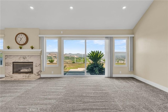 unfurnished living room featuring carpet flooring, recessed lighting, baseboards, and a premium fireplace