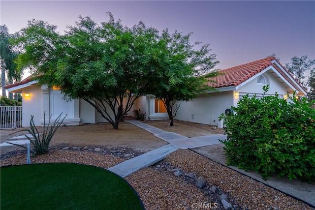 obstructed view of property featuring a tile roof, fence, and stucco siding