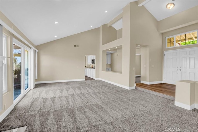 unfurnished living room featuring visible vents, baseboards, high vaulted ceiling, and carpet flooring