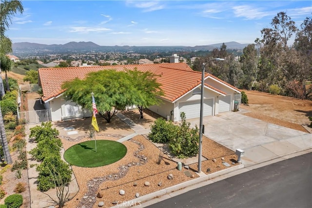 view of front of house with fence, a tile roof, stucco siding, driveway, and a mountain view