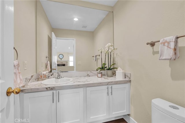 half bathroom with vanity, toilet, and visible vents