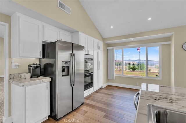 kitchen with visible vents, stainless steel fridge with ice dispenser, light wood-type flooring, lofted ceiling, and white cabinetry