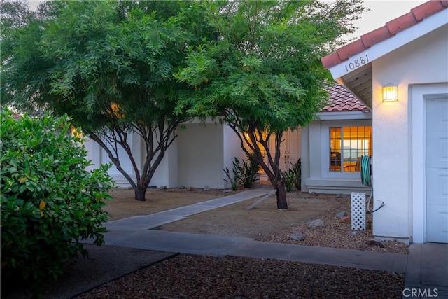 view of side of home with stucco siding and a tile roof