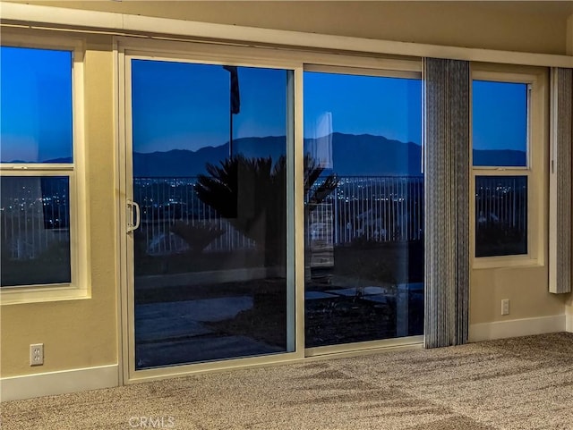 doorway to outside featuring baseboards and carpet floors