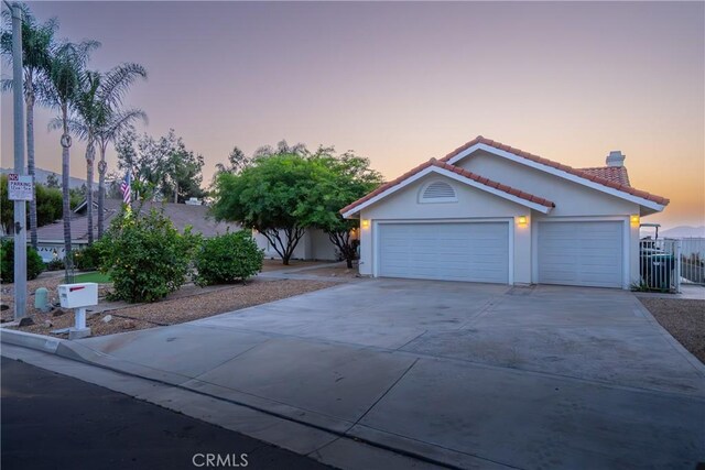 view of front of property with fence, stucco siding, concrete driveway, a garage, and a tile roof