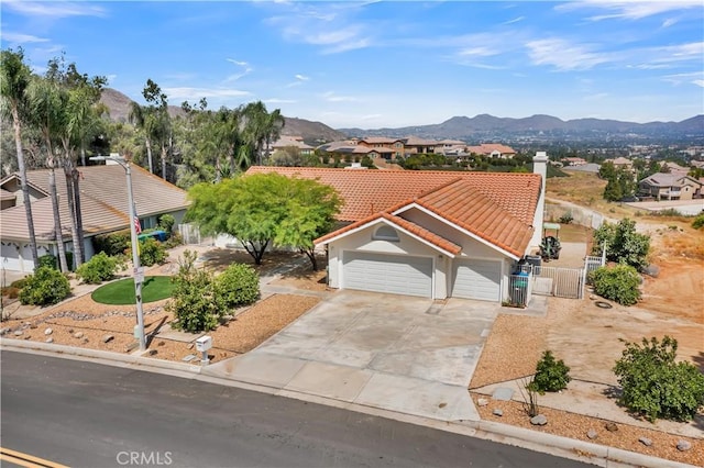 view of front facade with a tiled roof, stucco siding, driveway, a mountain view, and a gate