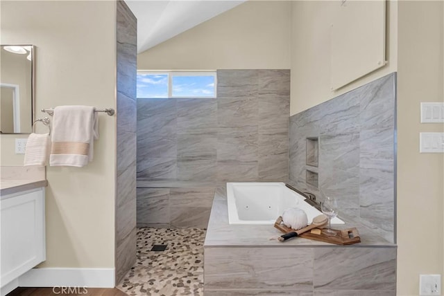 bathroom with a walk in shower, a jetted tub, vanity, and vaulted ceiling