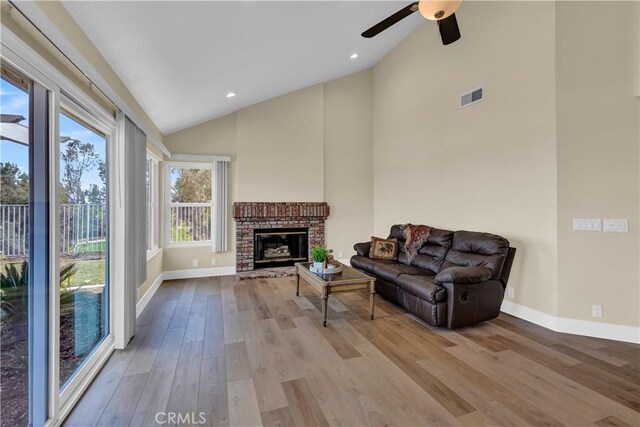 living area with visible vents, a brick fireplace, baseboards, and wood finished floors