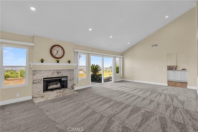 unfurnished living room with a fireplace, carpet, baseboards, and high vaulted ceiling