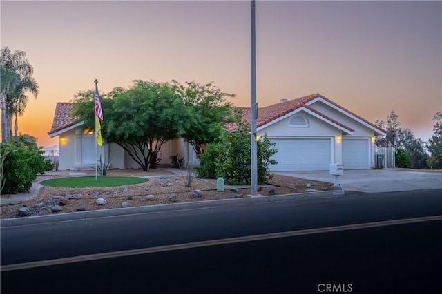 view of front of home with concrete driveway, a tiled roof, a garage, and stucco siding