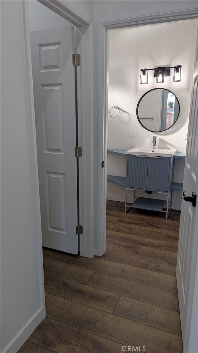 bathroom featuring baseboards, wood finished floors, and vanity