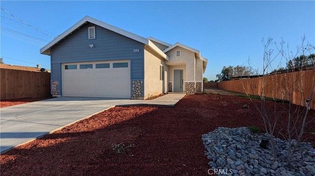 view of front of house featuring stone siding, concrete driveway, an attached garage, and fence