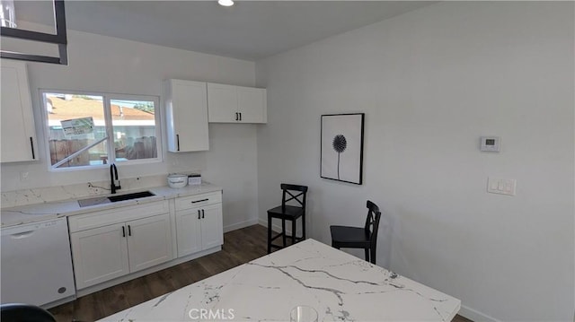 kitchen with a sink, light stone counters, dark wood finished floors, white cabinets, and white dishwasher