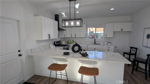 kitchen featuring range hood, a peninsula, dark wood-style flooring, a sink, and gas range