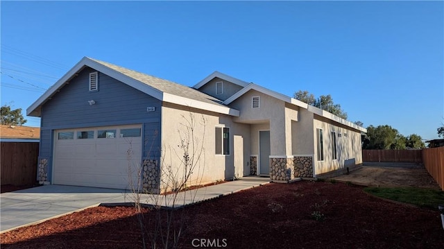 view of front facade with stucco siding, driveway, stone siding, fence, and a garage