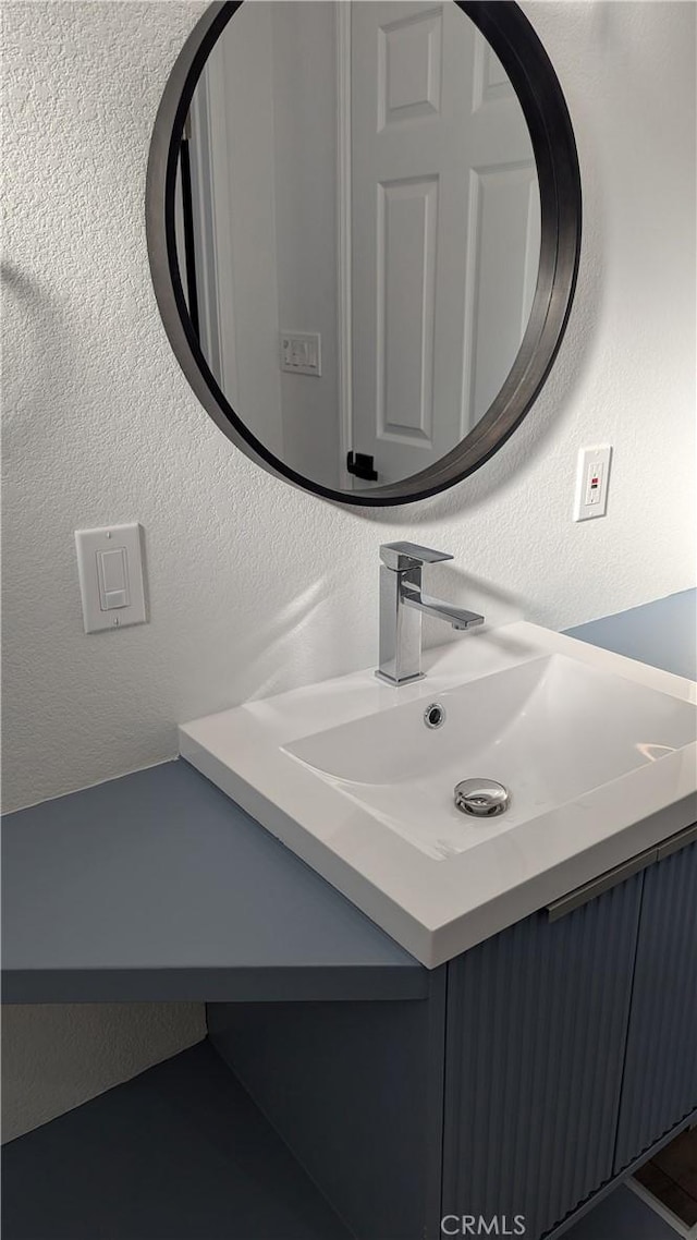 bathroom featuring vanity and a textured wall