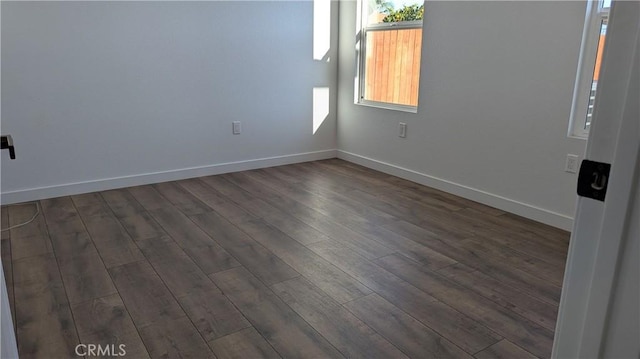 unfurnished room with dark wood finished floors and baseboards