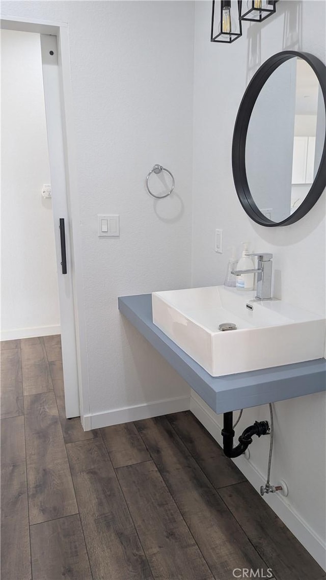 bathroom with a sink, baseboards, and wood finished floors