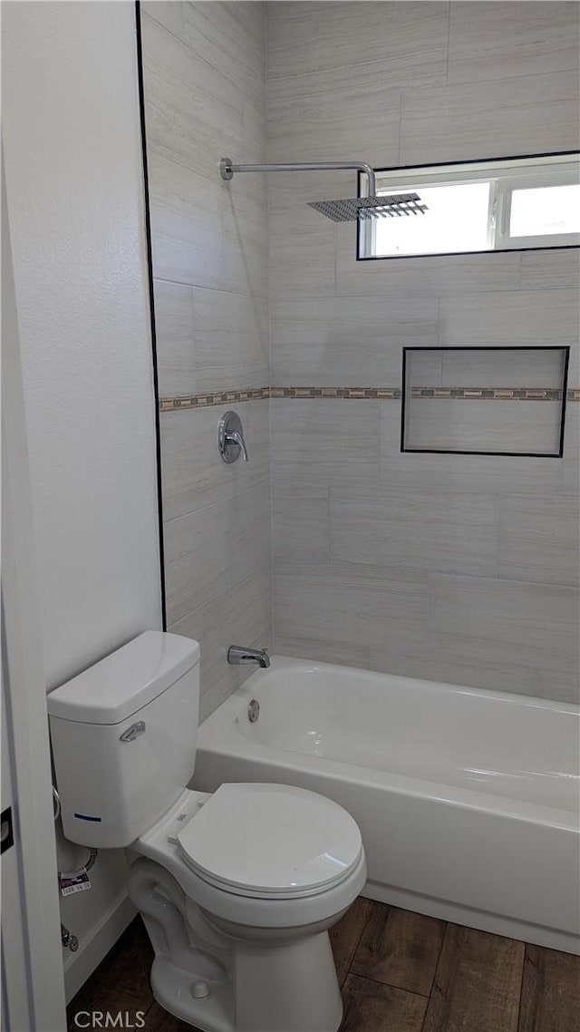 bathroom with bathtub / shower combination, toilet, and wood finished floors