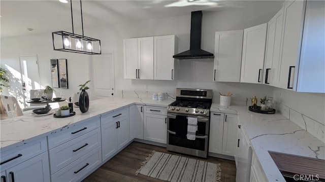 kitchen featuring light stone countertops, a peninsula, range with two ovens, white cabinetry, and wall chimney exhaust hood