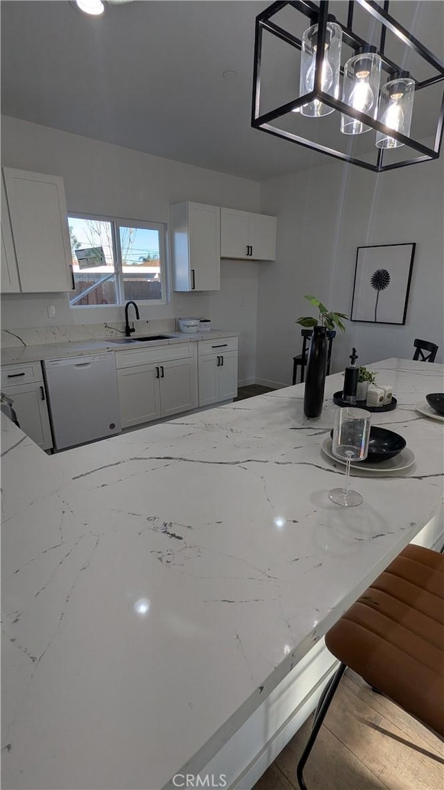 kitchen featuring light stone countertops, dishwasher, hanging light fixtures, white cabinetry, and a sink